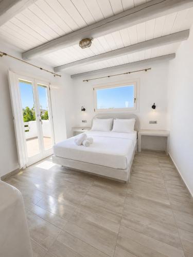 a white bedroom with a white bed and a window at My Villa Naxos in Naxos Chora