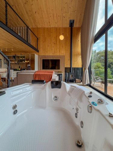 a large white bath tub in a room with windows at Villa Alpina - Cabanas Conceito - Vale dos Vinhedos in Bento Gonçalves