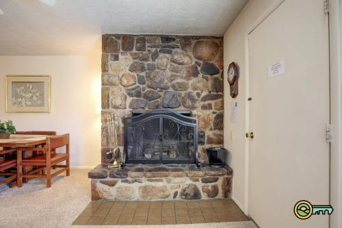 a stone fireplace in a living room with a table at Aspen East Unit #122 in Basye