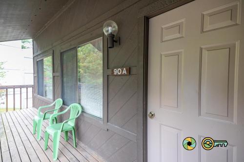 a porch with two green chairs and a door at Senedo Springs Duplex #90A in Basye