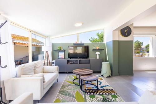 a living room with a couch and a tv at Ensemble Villa et Studio Piscine Proche Plage in Valras-Plage