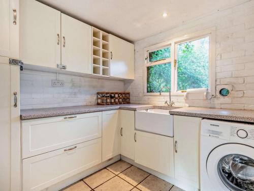 a kitchen with white cabinets and a washing machine at 4 Bed in Ringwood oc-92557 in Burley