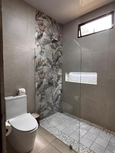 a bathroom with a toilet and a glass shower at Casa Melda Walk to the Beach & Gandoca-ManzanillO in Manzanillo