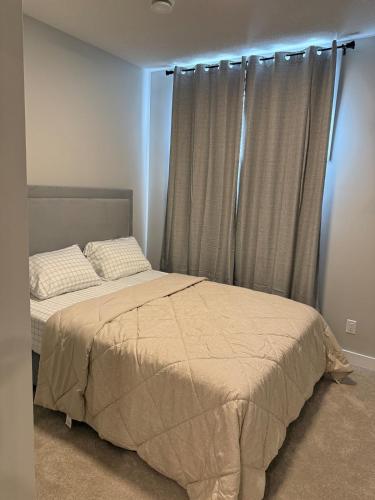 a bedroom with a bed and a window with curtains at A place to call a home in YYC