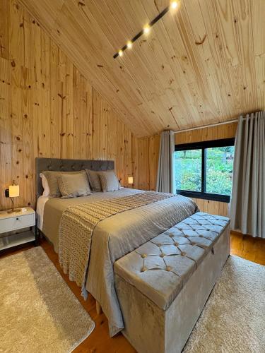a bedroom with a bed in a room with wooden walls at Villa Alpina - Cabanas Conceito - Vale dos Vinhedos in Bento Gonçalves