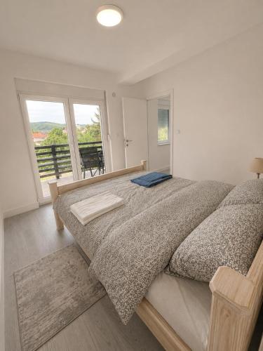 a bedroom with a large bed and a balcony at White House apartmani in Vrdnik