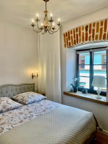 a bedroom with a bed with a chandelier and a window at Lublin Aura Residence in Lublin