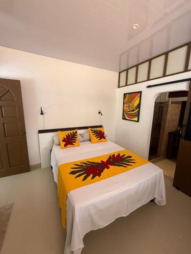 a bedroom with a large bed with a yellow blanket at Aremiti - Fare Orotia in Taputapuapea
