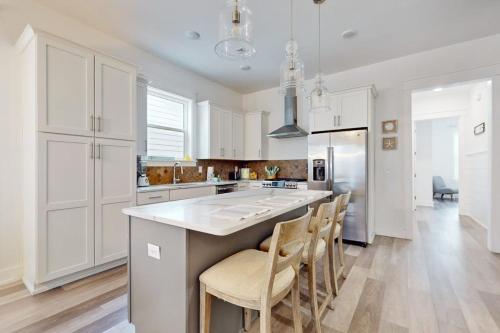 a kitchen with white cabinets and a kitchen island with chairs at New-Build with Pool Walk to Beach in Santa Rosa Beach