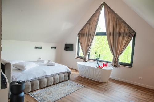 ein Schlafzimmer mit Bett, Badewanne und Fenstern in der Unterkunft Infinity View Chalet in Valea Doftanei