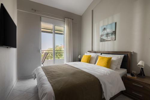 a bedroom with a bed with yellow pillows and a window at Sakis 2 in Polychrono