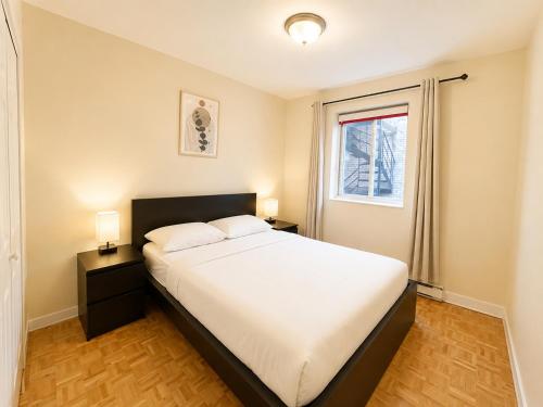 a bedroom with a bed with two night stands and a window at APARTMENT HOTEL ST-DENIS in Montreal