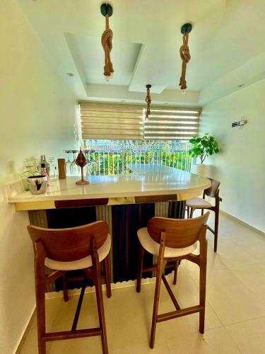a kitchen with a bar with chairs and a table at Residencial Paradise in San Francisco de Macorís