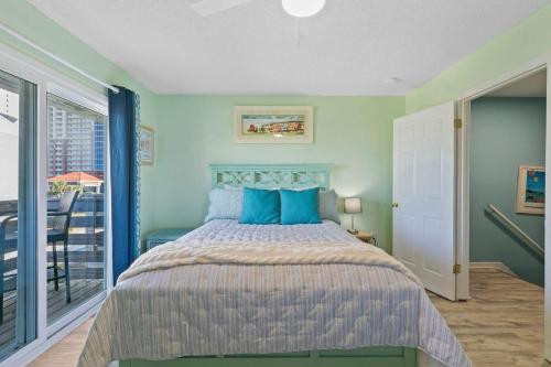 a bedroom with a bed with blue pillows and a balcony at Spacious 2BR Condo with Pool Across from the Beach in Gulf Shores