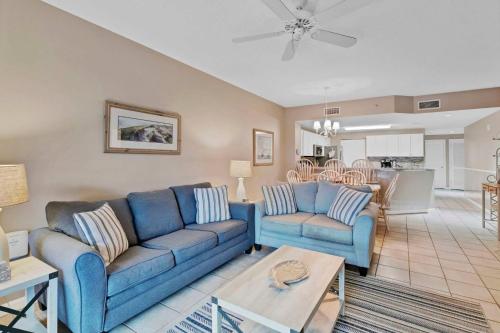 a living room with two blue couches and a kitchen at 3BR 4BA Ground Floor Gulf Getaway in Gulf Shores