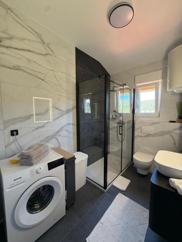 a bathroom with a shower and a washing machine at Apartments Angela Rab in Supetarska Draga