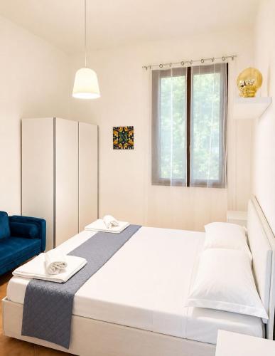 a bedroom with a large white bed and a blue chair at Le case di Rebecca in Palermo