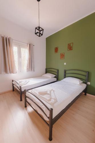 two beds in a room with green walls at Zoumperi Summer House in Nea Makri