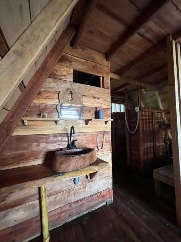 a bathroom with a sink in a log cabin at Origen ZelvaMar BahiaSolano in Bahía Solano