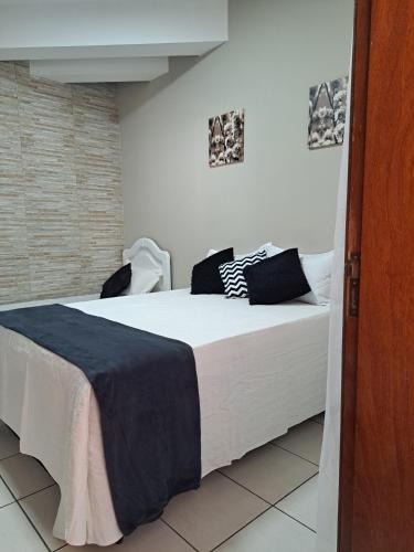 a bedroom with a large white bed with black pillows at Quarto confortável em Diamantina in Diamantina