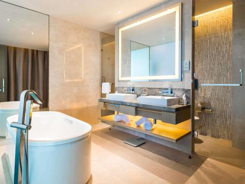 a bathroom with two sinks and a tub and a mirror at NOVOTEL Jinji Lake Suzhou SIP in Suzhou
