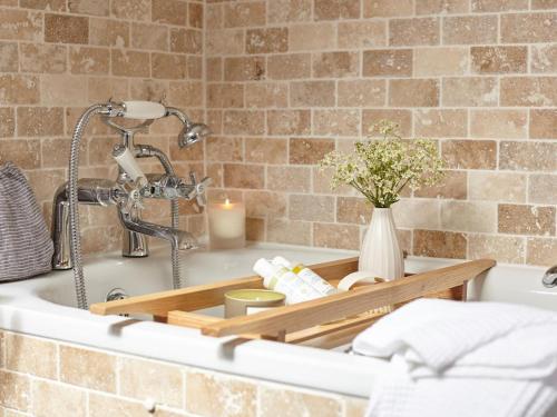a bathtub with a candle and a vase of flowers at 3 Bed in Niton oc-73299 in Niton