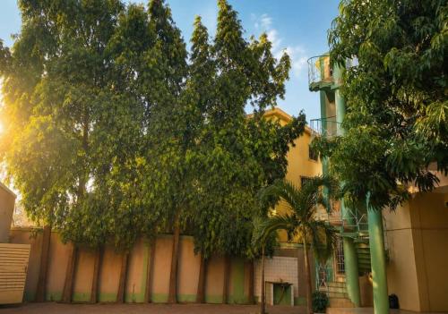 a building with a tree in front of a fence at Lilia Business Hotel in Ouagadougou
