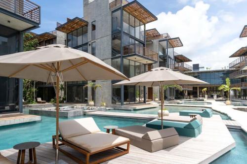 a pool with chairs and umbrellas next to a building at Ideal Location with Cenote Pools Gym Restaurant in Tulum