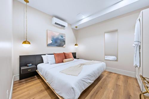 a bedroom with a large white bed with orange pillows at Casa Hotels Gerrard Private Basement Suite in Toronto