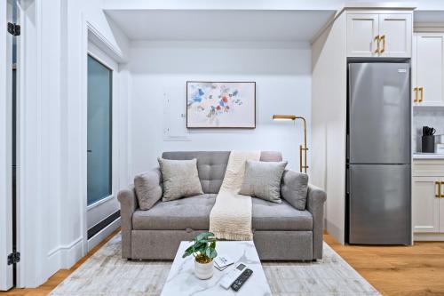 a living room with a couch and a refrigerator at Casa Hotels Gerrard Private Basement Suite in Toronto