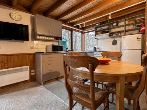 a kitchen with a wooden table and chairs in a kitchen at Bindi - Alpine Getaways's Chalet at Tower Rd in Dinner Plain