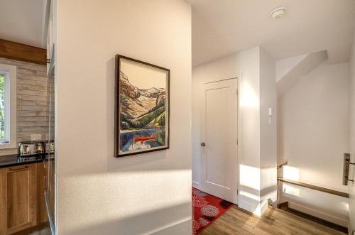a kitchen with a painting on the wall and a hallway at Käbane Nova - La Chaleureuse in Baie-Saint-Paul