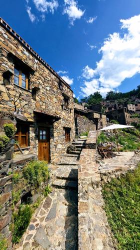 an old stone building with a stone walkway in front at Cantinho do Talasnal in Talasnal