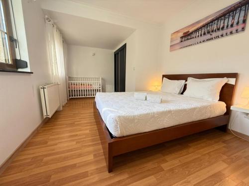 a bedroom with a large bed with white sheets and wooden floors at Casa Terra Nova - Gerês in Terras de Bouro