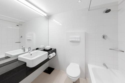 a white bathroom with a sink and a toilet at Crowne Plaza Queenstown by IHG in Queenstown