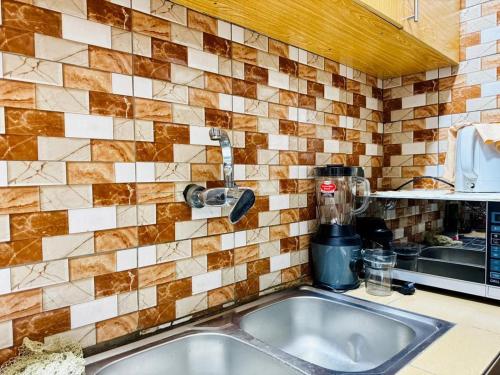 a kitchen sink with a mixer on a tiled wall at Appartement meublé service in Cotonou