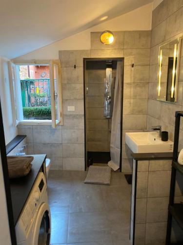 a bathroom with a shower and a sink and a washing machine at Casa Alice in Muggia