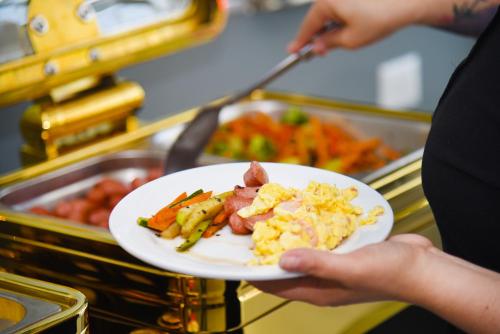 a person holding a plate of food on a buffet at Hotel HW Libertad in Santiago