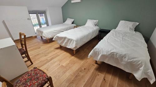 a room with two beds with white sheets and a chair at La Valdonnière in Esnoms-au-Val