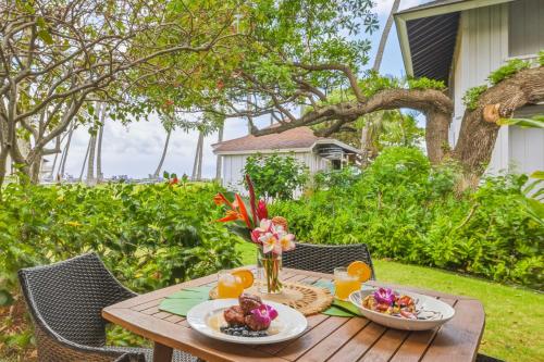 a wooden table with two plates of food on it at Kiahuna 183 Ground Floor Ocean View PBAC in Koloa