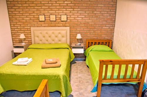 two beds in a room with green sheets at Las Magnolias in Embalse
