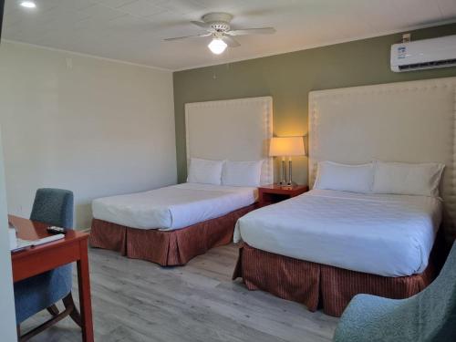 a hotel room with two beds and a desk at Manor Motel in Southampton