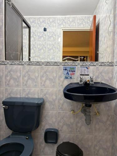 a bathroom with a black toilet and a sink at Hotel Romanza in Bogotá