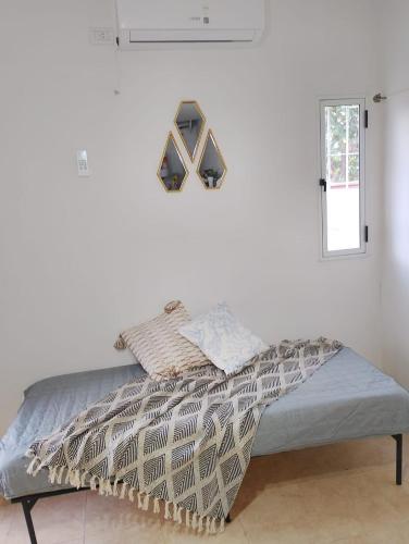 a bed in a room with a white wall at Nido del Sol in Pocito