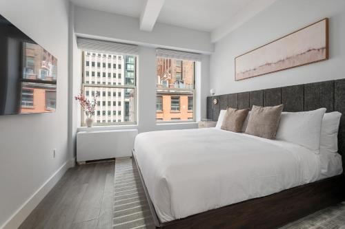 a bedroom with a large white bed and two windows at 17John Residences in New York