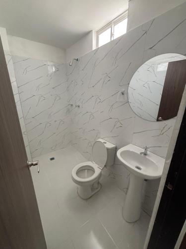 a white bathroom with a toilet and a sink at El Encanto in Valledupar