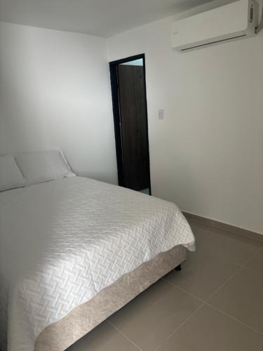 a bedroom with a white bed and a black door at El Encanto in Valledupar