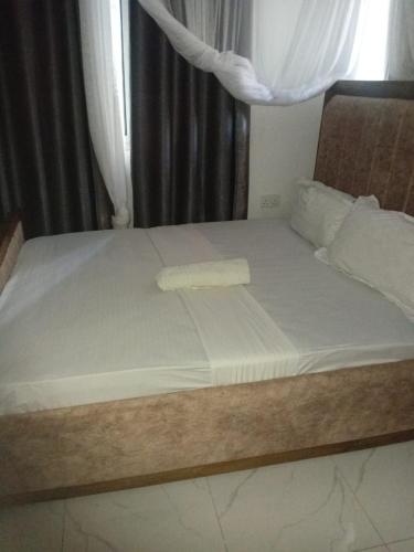 a bed with a wooden frame and white sheets at Lila Homes in Bamburi