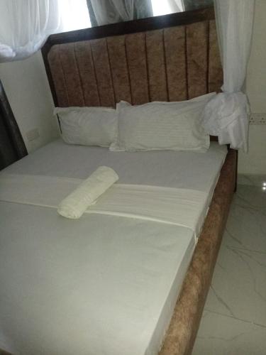 a bed with a wooden headboard and white sheets at Lila Homes in Bamburi
