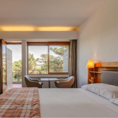 a hotel room with a bed and a desk and a window at Parque do Rio Ofir Hotel in Esposende